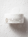 Rare Elements Essential Conditioner jar on a textured white background with water droplets.